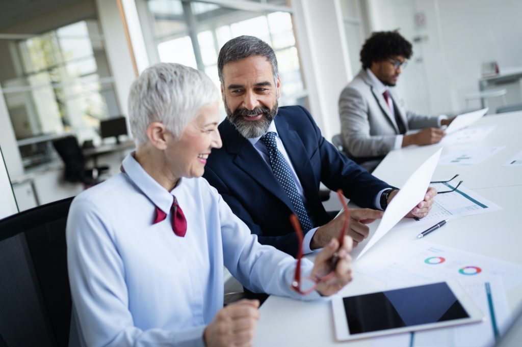 Portrait of happy business people discussing together in office
